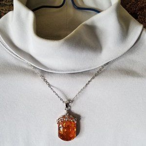Attractive, faux amber pendant on a silver colored chain.
